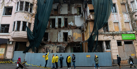 Menschen stehen in der Ukraine in Charkiw vor einem beschädigten Haus