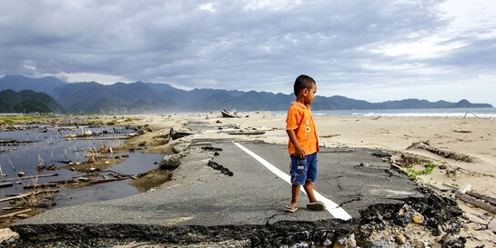 Ein Kind an einer Straße, die vom Tsunami zerstört wurde