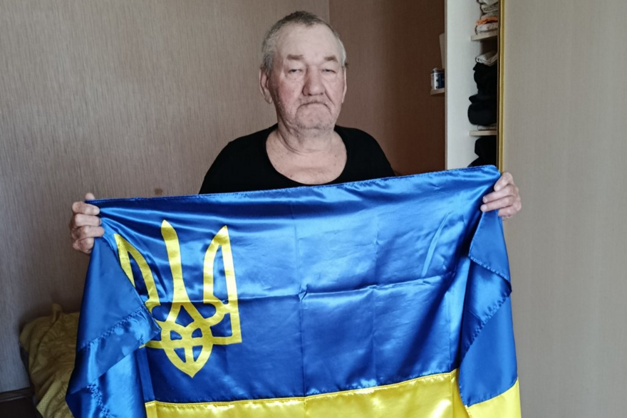 Ein älterer Mann hält eine ukrainische Flagge in den Händen