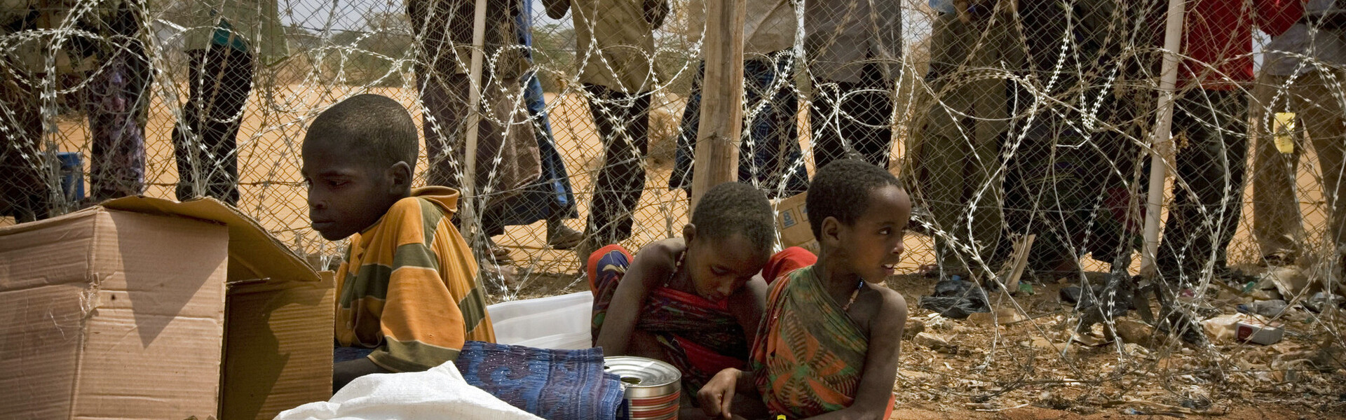 Geflüchtete Menschen aus Somalia warten hinter Stacheldraht 