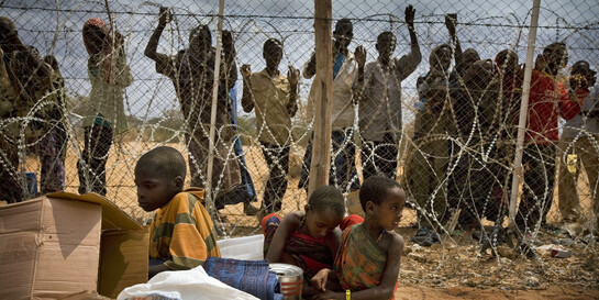 Geflüchtete Menschen aus Somalia warten hinter Stacheldraht 