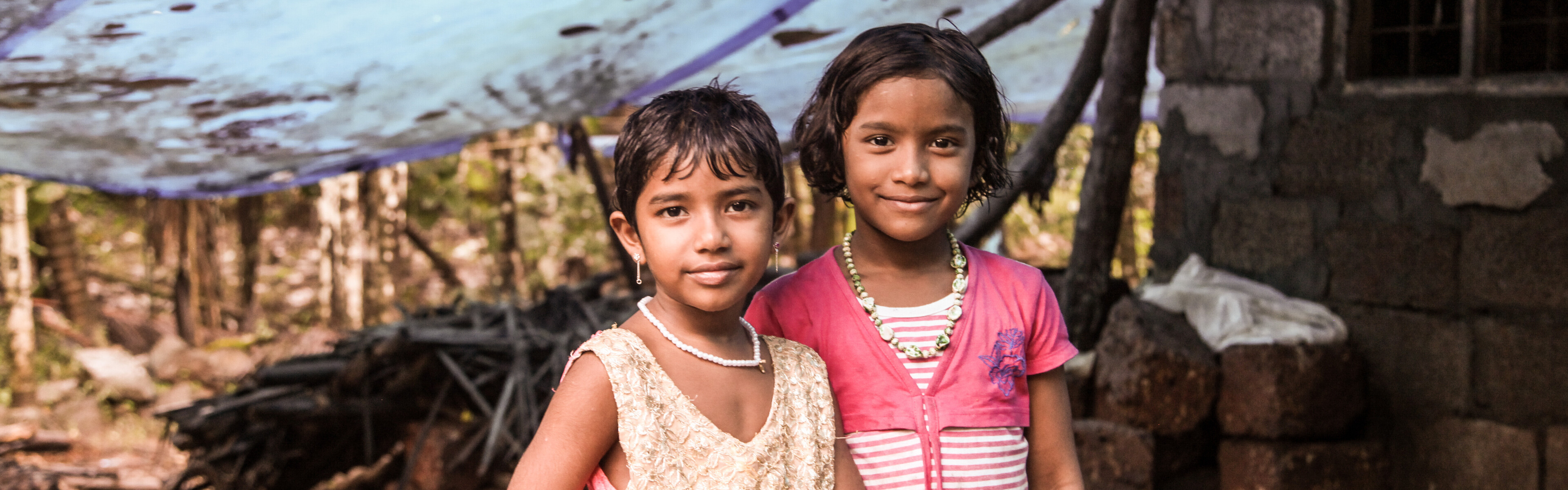 Zwei Mädchen stehen in Indien vor ihrem von der Flut zerstörten Zuhause 