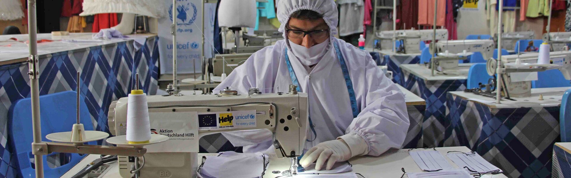 Eine Frau in Afghanistan näht im Schutzanzug eine Atemschutzmaske gegen die Verbreitung des Coronavirus 