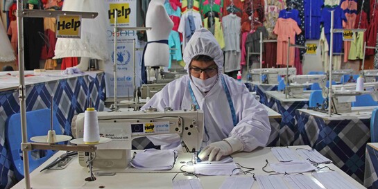 Eine Frau in Afghanistan näht im Schutzanzug eine Atemschutzmaske gegen die Verbreitung des Coronavirus 