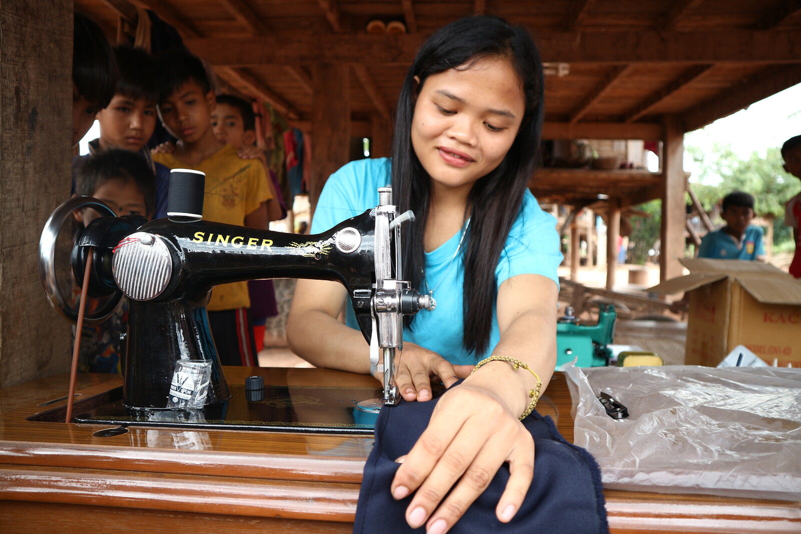 Eine Frau in Laos fertigt an der Nähmaschine ein Kleidungsstück in ihrer eigenen Schneiderei an