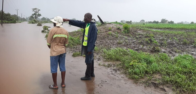 Zwei Helfer stehen nach dem Zyklon Gezani an einer überschwemmten Straße in Mosambik.