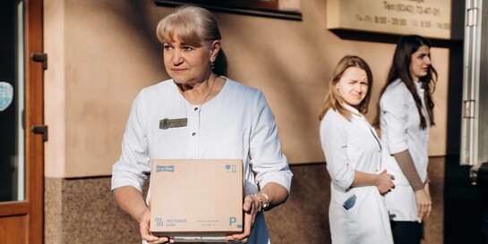 Eine Helferin hält in der Ukraine ein Paket mit Hilfsgütern in der Hand