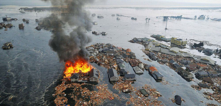 Vom Tsunami weggeschwemmte Häuser sind in Brand geraten. © REUTERS/KYODO Kyodo