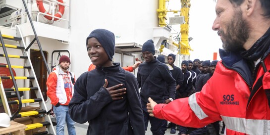 Ein Helfer mit Flüchtlingen, die im Mittelmeer aus Seenot gerettet wurden