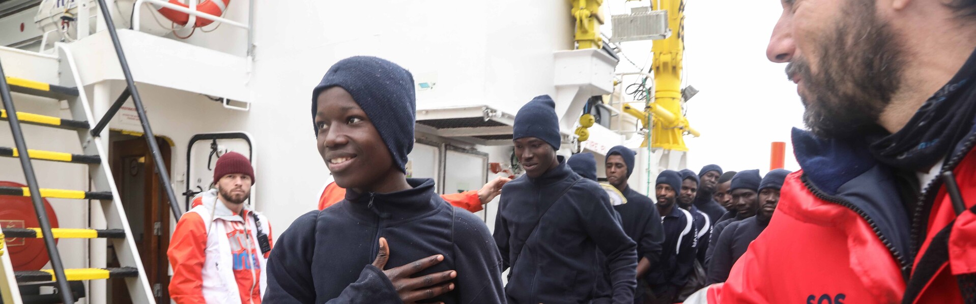Ein Helfer mit Flüchtlingen, die im Mittelmeer aus Seenot gerettet wurden