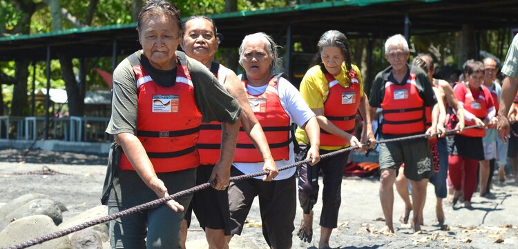 Eine Gruppe von Männern und Frauen mit Rettungsweste auf den Philippinen hangeln sich an einem Tau entlang Eine Gruppe von Männern und Frauen mit Rettungsweste auf den Philippinen hangeln sich an einem Tau entlang