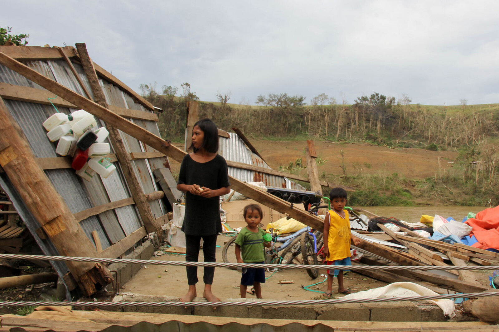 Frau und Kinder vor einem zerstörtes Haus nach Taifun Mangkhut auf den Philippinen