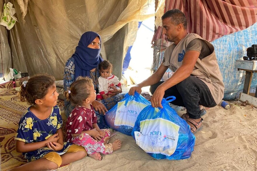 Ein Helfer verteilt Lebensmittel an eine Familie in Gaza