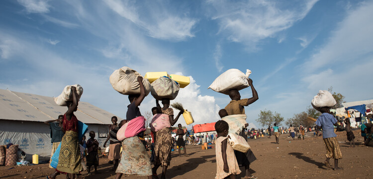 Geflüchtete Menschen aus dem Südsudan tragen ihr Hab und Gut in Bündeln auf dem Kopf Geflüchtete Menschen aus dem Südsudan tragen ihr Hab und Gut in Bündeln auf dem Kopf