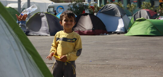 In Griechenland steht ein Kind in einem Flüchtlingslager.