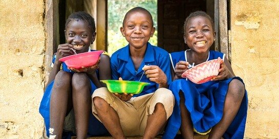 Drei Schulkinder in Sierra Leone nehmen eine Mahlzeit zu sich