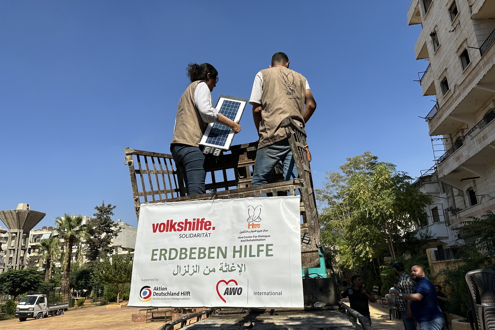 Helfer der Organisation AWO International unterstützen beim Wiederaufbau und montieren Solarlampen