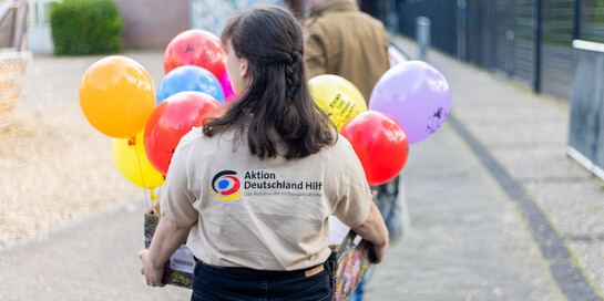 Eine Helferin trägt eine Kiste mit Luftballons