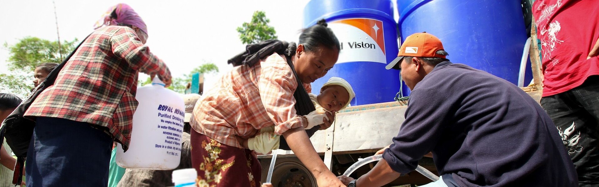 Personen und mit Trinkwasser gefüllte Wassertanks in Myanmar