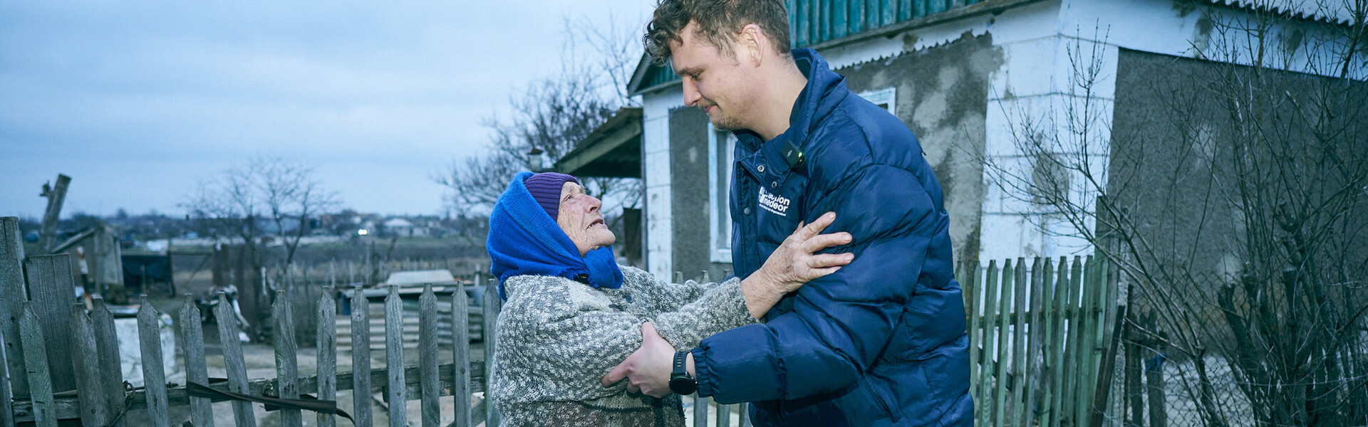Ein Helfer der Organisation action medeor beliefert eine ältere Frau in der Ukraine mit Gasflaschen