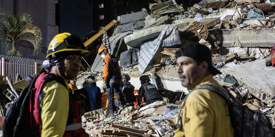Zwei Helfer stehen nach dem Erdbeben in Venezuela vor einem zerstörten Gebäude