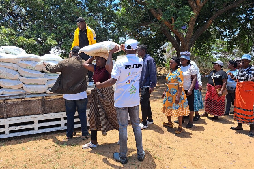 Frauen und Männer in Simbabwe entladen eine Hilfslieferung Frauen und Männer in Simbabwe entladen eine Hilfslieferung