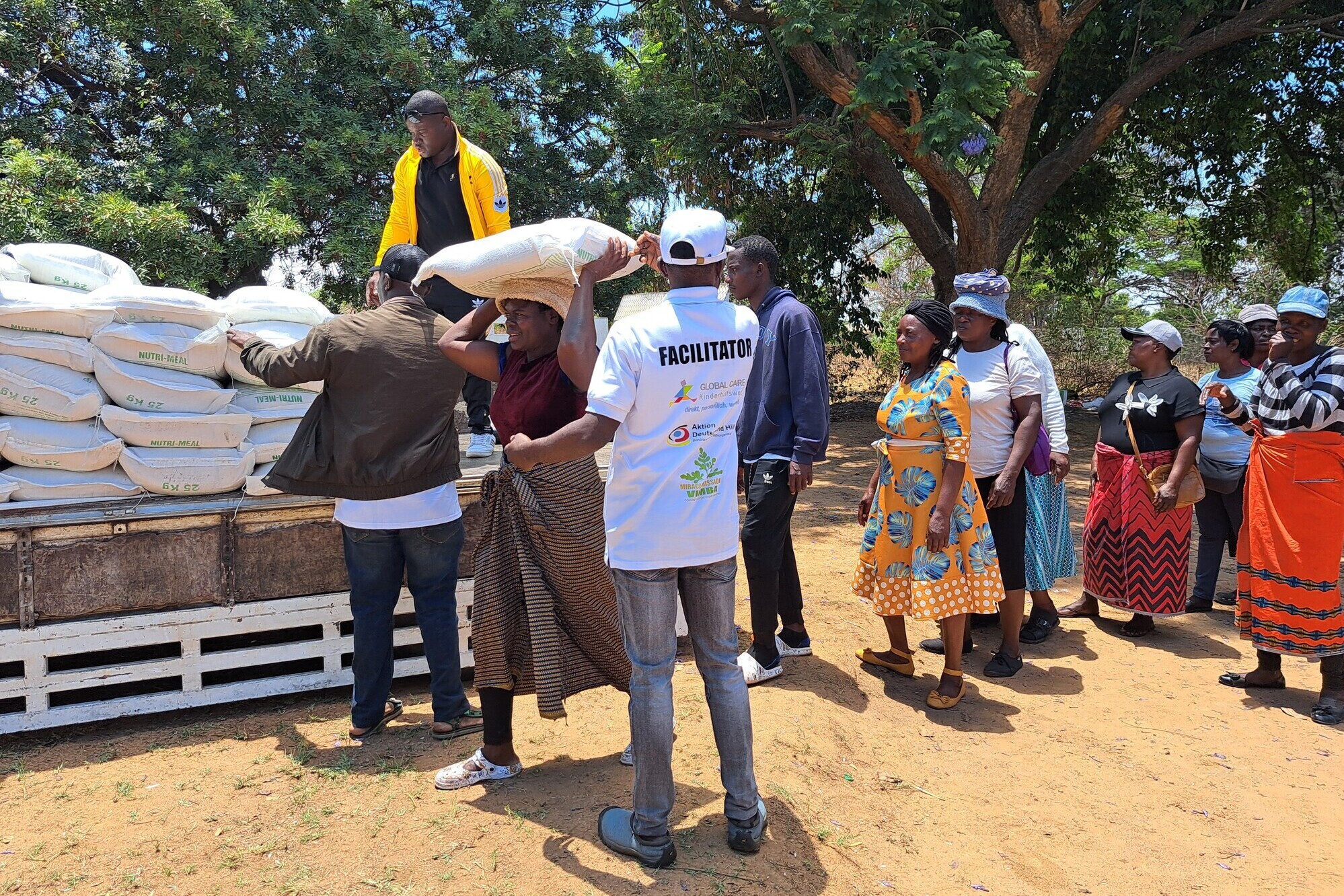 Frauen und Männer in Simbabwe entladen eine Hilfslieferung Frauen und Männer in Simbabwe entladen eine Hilfslieferung