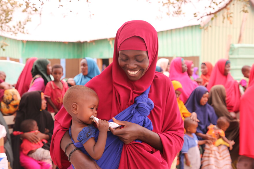 Frau mit Kind, das Notfallnahrung gegen Hunger erhalten hat, in Somalia Frau mit Kind, das Notfallnahrung gegen Hunger erhalten hat, in Somalia