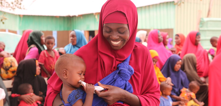 Frau mit Kind, das Notfallnahrung gegen Hunger erhalten hat, in Somalia Frau mit Kind, das Notfallnahrung gegen Hunger erhalten hat, in Somalia