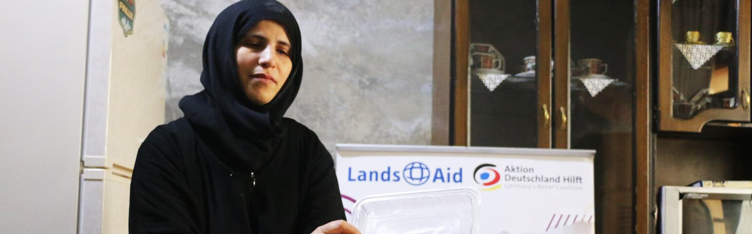 Afaf hält eine Dose mit ihrem Gebäck in der Hand