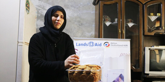 Afaf hält eine Dose mit ihrem Gebäck in der Hand