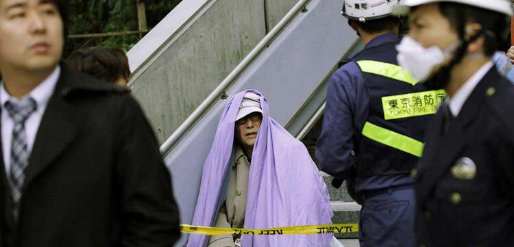 Erdbeben Japan, ein alter Mann sitzt nach seiner Evakuierung aus dem Gebäude auf der Treppe.