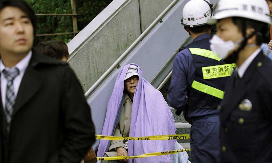 alter-mann Erdbeben Japan, ein alter Mann sitzt nach seiner Evakuierung aus dem Gebäude auf der Treppe.