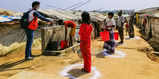 Ein Helfer von World Vision weist an einer Wasserstation in einem Flüchtlingslager in Bangladesch die Campbewohner ein 