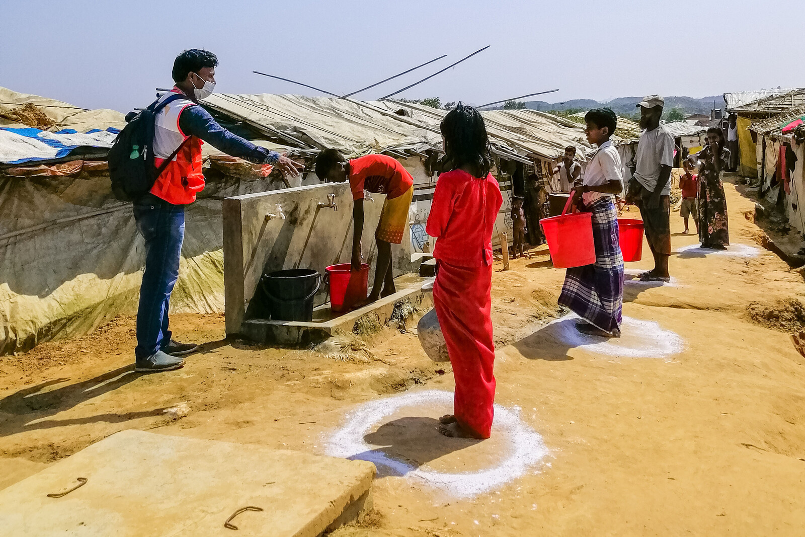 Ein Helfer von World Vision weist an einer Wasserstation in einem Flüchtlingslager in Bangladesch die Campbewohner ein 