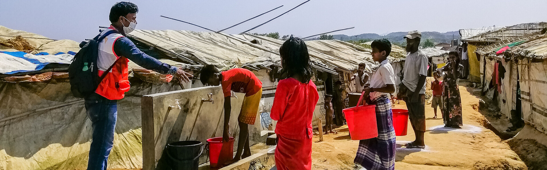 Ein Helfer von World Vision weist an einer Wasserstation in einem Flüchtlingslager in Bangladesch die Campbewohner ein 