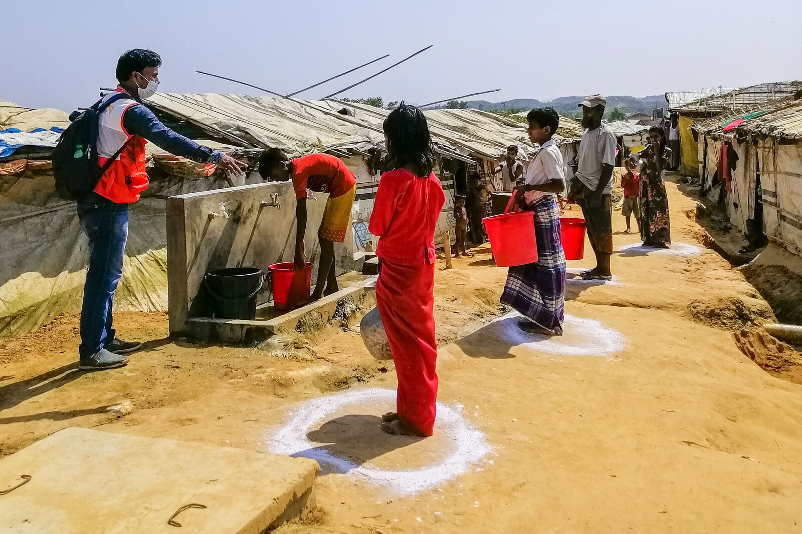 Ein Helfer von World Vision weist an einer Wasserstation in einem Flüchtlingslager in Bangladesch die Campbewohner ein 