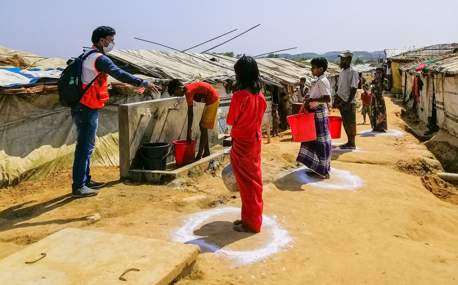 Ein Helfer von World Vision weist an einer Wasserstation in einem Flüchtlingslager in Bangladesch die Campbewohner ein 