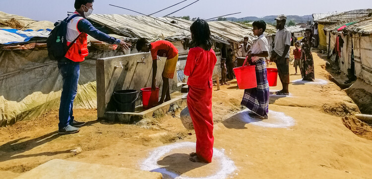 Ein Helfer von World Vision weist an einer Wasserstation in einem Flüchtlingslager in Bangladesch die Campbewohner ein 