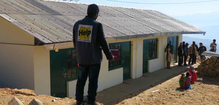 Ein Mitarbeiter der Hilfsorganisation Help vor der neuen Schule in Nepal Ein Mitarbeiter der Hilfsorganisation Help vor der neuen Schule in Nepal