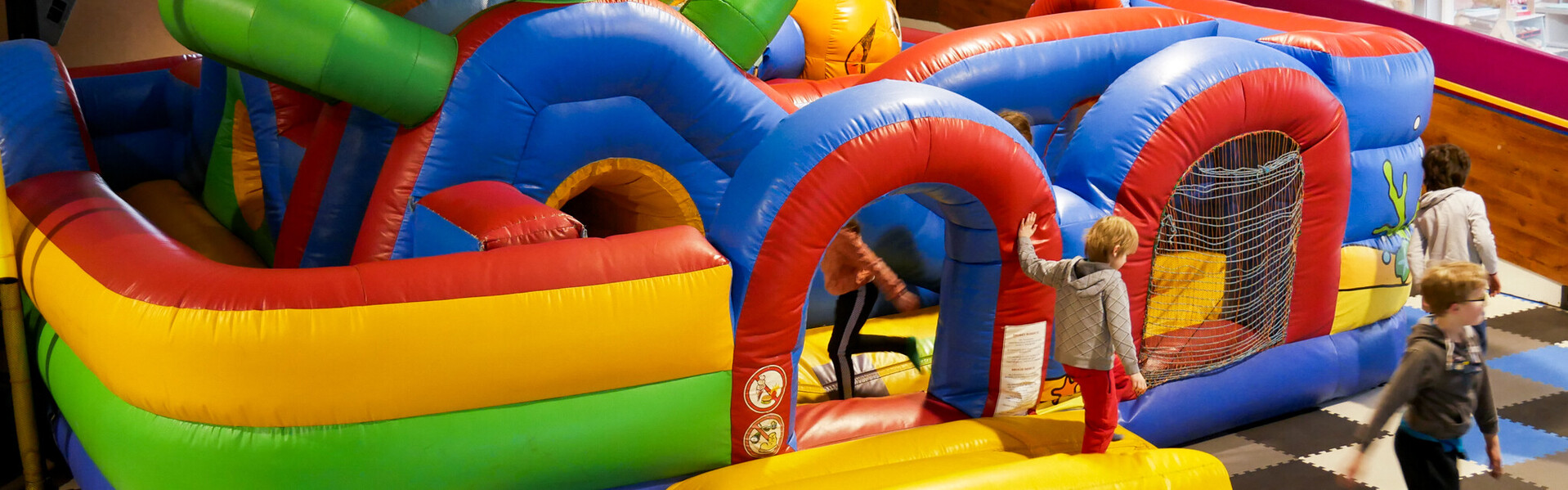 Kinder toben auf der Hüpfburg eines Spielplatzes im Flutgebiet