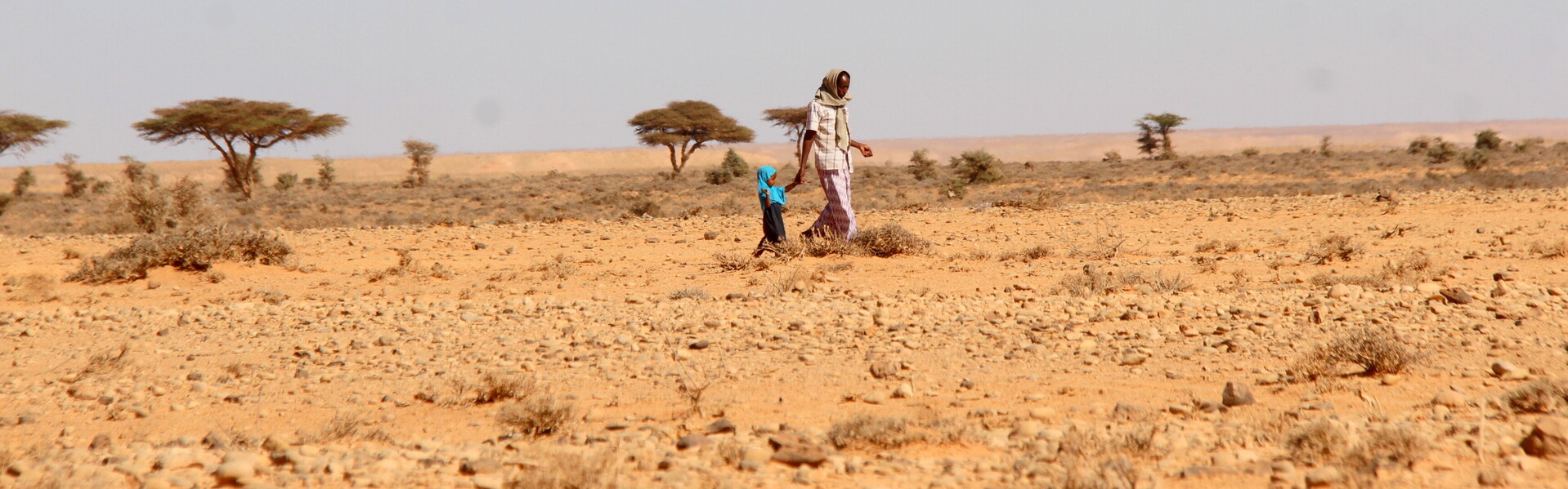 Eine Frau mit ihrer Tochter laufen durch ein ausgetrocknetes Gebiet in Somalia