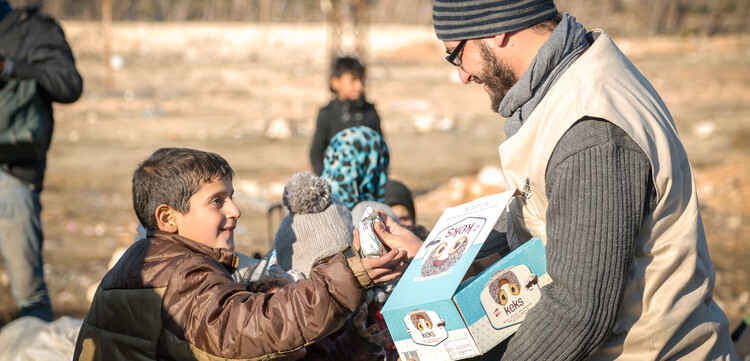 Ein Helfer verteilt in Syrien Nahrungsmittel an einen Jungen Ein Helfer verteilt in Syrien Nahrungsmittel an einen Jungen