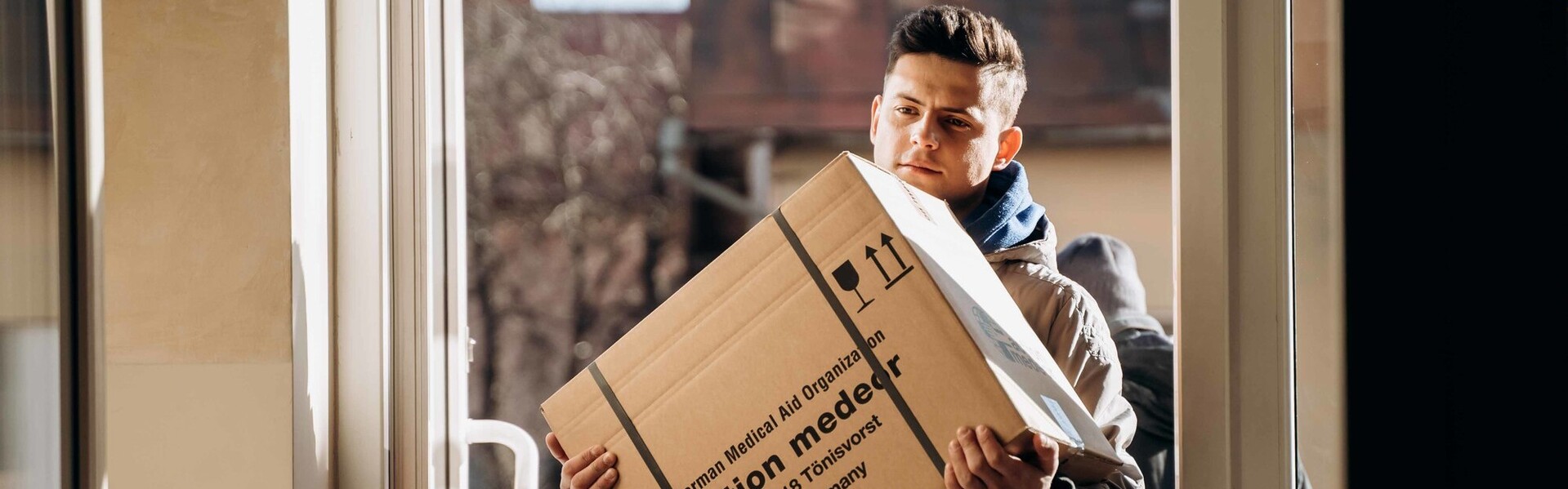 Ein Helfer trägt ein Paket mit Hilfslieferungen von der Organisation action medeor
