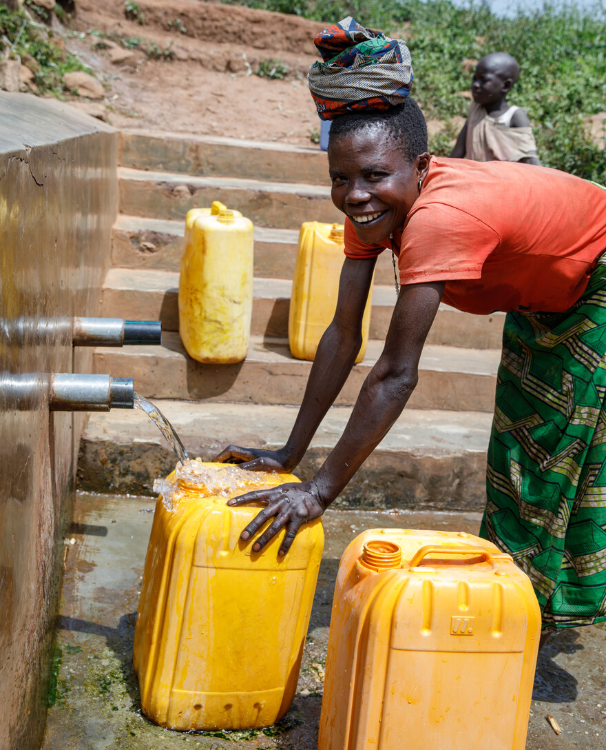 Eine Frau in füllt an einer Wasserstelle in Afrika einen Kanister mit Wasser auf