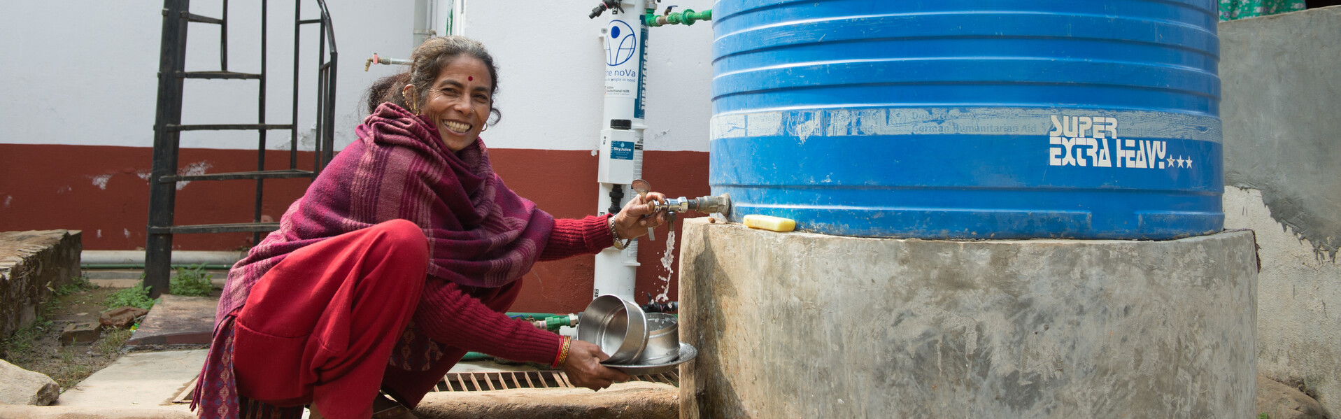 Nach dem Erdbeben in Nepal wäscht siche eine Frau an Wassertanks die Hände.