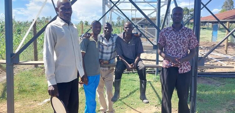 Vier Männer stehen in West-Kenia vor einem neues Wasser-Bohrturm Vier Männer stehen in West-Kenia vor einem neues Wasser-Bohrturm