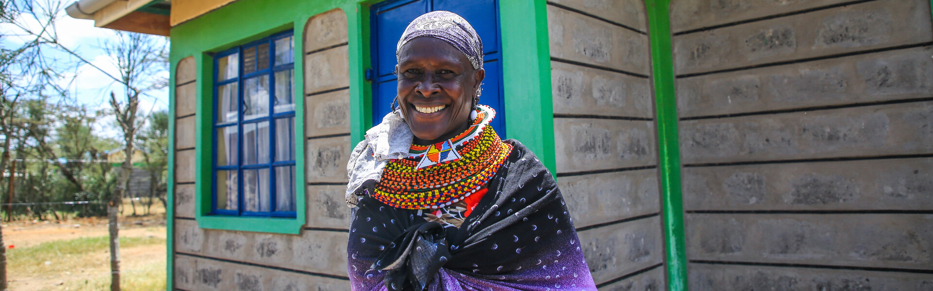 A female massai in Kenya stands in front of a house