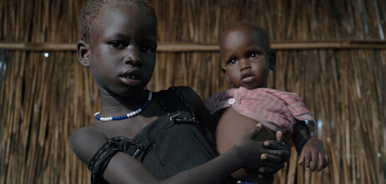 Ein Kind hält ein Baby im Arm im Südsudan. Beide sind Flüchtlinge.