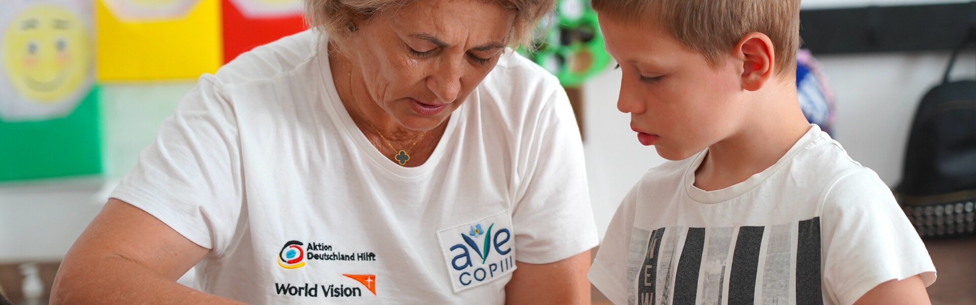 Eine Helferin der Organisation Ave Copiii arbeitet mit einem Kind gemeinsam an einem Bastelprojekt